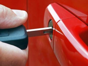 Gros plan d'une main insérant une clé de voiture dans la serrure d'une portière de voiture rouge à Ste-Julie, soulignant l'assurance automobile et la sécurité au quotidien.