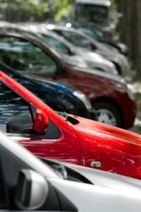 Une rangée de voitures garées de différentes couleurs, dont le rouge, le bleu et le gris, sont alignées étroitement les unes contre les autres le long d'une rue bordée d'arbres à Beloeil pendant la journée, offrant un aperçu de la vie quotidienne et des besoins automobiles en matière d'assurance.